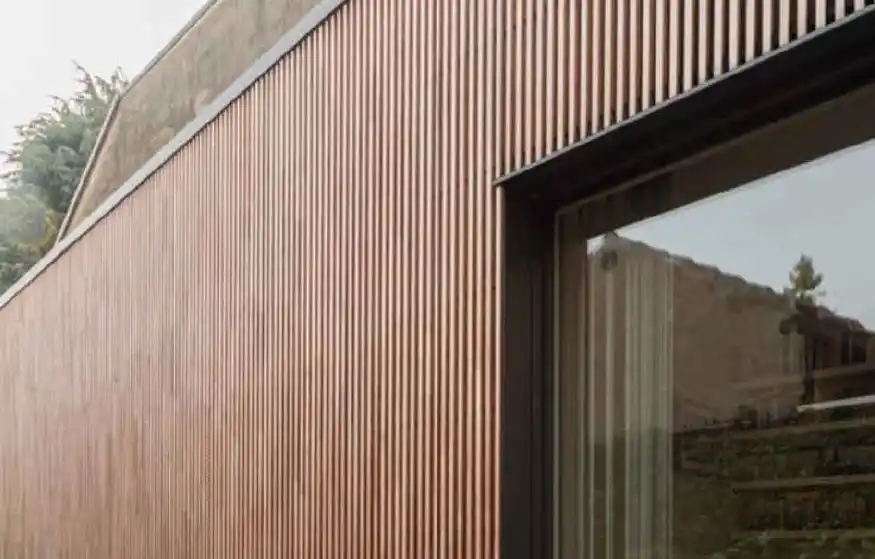 Fachada de edificio revestida con lambrín WPC oscuro, mostrando su resistencia a la intemperie y diseño moderno en Atlixco.