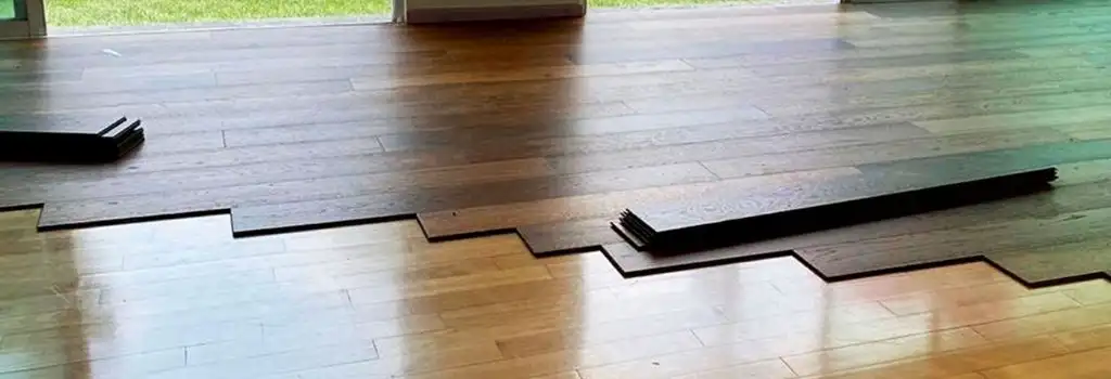 Proceso de instalación de duela de madera de ingeniería en interior, mostrando tablones ya colocados y el material a instalar. Destaca el acabado limpio y rápido del servicio de Grupo Orvi.