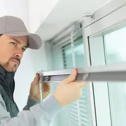 Técnico certificado instalando persianas enrollables con precisión en residencia de Puebla - Servicio profesional a domicilio Grupo Orvi con herrajes de acero inoxidable